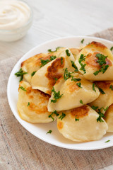 Homemade traditional polish fried potato pierogies on a white plate, low angle view. Close-up.