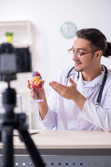 Young male doctor cardiologist recording video for his blog