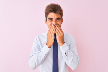 Young handsome businessman wearing shirt and tie standing over isolated pink background laughing and embarrassed giggle covering mouth with hands, gossip and scandal concept