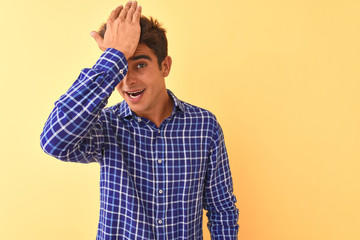 Young handsome man wearing casual shirt standing over isolated yellow background surprised with hand on head for mistake, remember error. Forgot, bad memory concept.