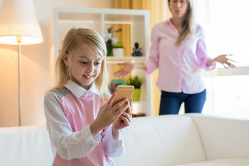 Single annoyed mom talks to her daughter put down smartphone