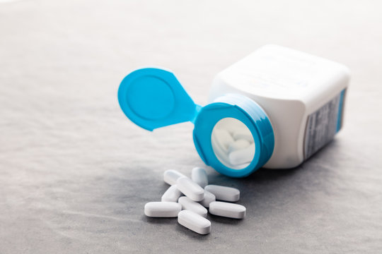 Pharmaceutical medicine tablets, pills, capsules, drugs on grey background in white and blue plastic jar. Pill bottle background use in presentations, education manuals, design, 3D illustration