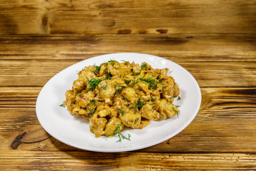 Stewed mushrooms with sour cream on wooden table