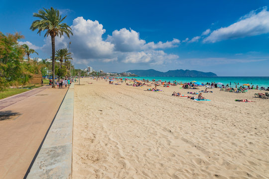 People relax at seaside sand beach in Cala Millor on Mallorca island, Spain