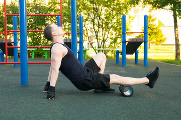 man outdoors, doing sports and doing massage roller, calf muscle