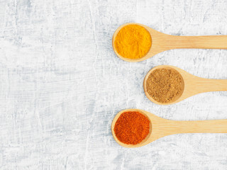 Spices help maintain good health and improve appetite, top view on white concrete background. Red chili pepper, masala, turmeric in wooden spoon. Modern apothecary, naturopathy and ayurveda concept.