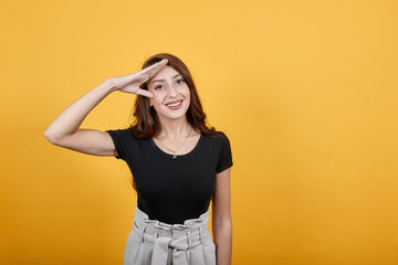 Girl doing military practice as she is saluting to her commanding officer in a frank way. She is happy as she is ready to follow someone's orders precisely.