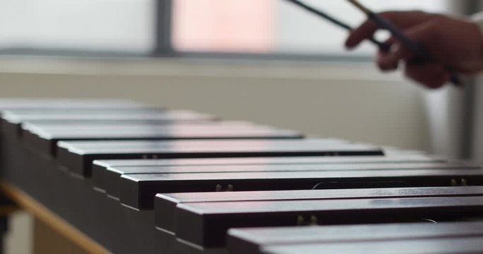 close up shot of marimba keyboard. percussionist hands playing this xylophone. many wooden bars and fast movements from the musician