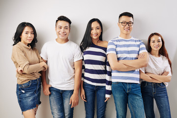 Portrait of young beautiful Asian people smiling and looking at camera when standing at wall in studio