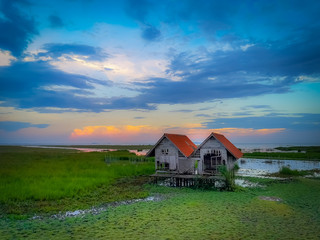 Old twin houses in the grass fields with beautiful clouds and sky during sunset time.