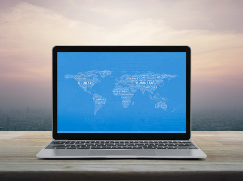 Global business words world map with modern laptop computer on wooden table over office city tower and skyscraper at sunset sky, vintage style, Global business online concept, Elements of this image f