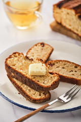 Banana bread. Freshly baked homemade banana pie with honey and butter on a light gray background
