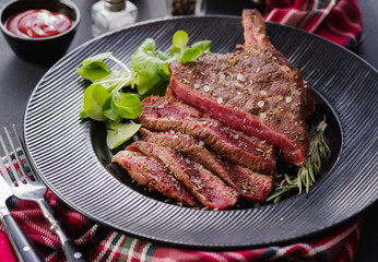 Steak on the bone. Rib eye. Tomahawk steak on the black plate with rosemary. Roasting - Rare. Entrecote