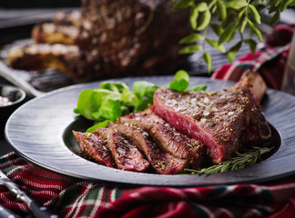 Steak on the bone. Rib eye. Tomahawk steak on the black plate with rosemary. Roasting - Rare. Entrecote