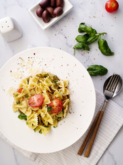 Farfalle pasta with parmesan, basil and cherry tomatoes. Italian Cuisine. Top view