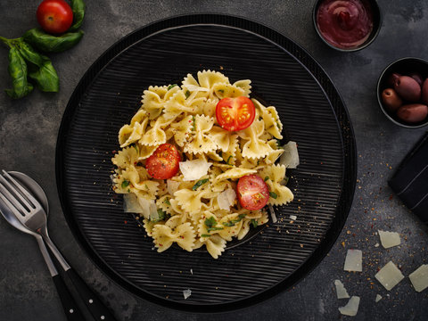 Farfalle pasta with parmesan, basil and cherry tomatoes. Italian Cuisine. Top view