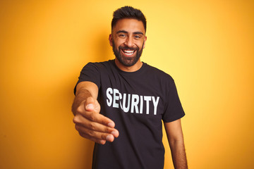 Arab indian hispanic safeguard man wearing security uniform over isolated yellow background smiling friendly offering handshake as greeting and welcoming. Successful business.