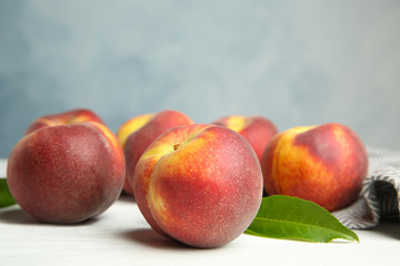 Fresh juicy peaches, leaves and fabric on white wooden table