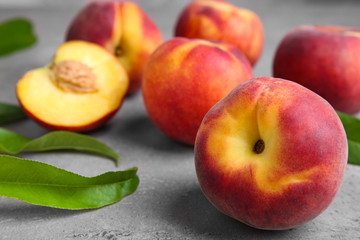 Fresh peaches and leaves on grey table