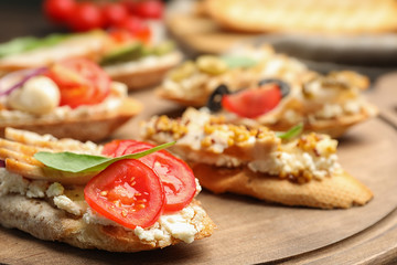 Delicious chicken bruschettas on wooden board, closeup