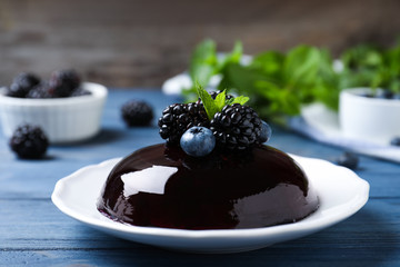 Delicious fresh jelly with berries on blue wooden table