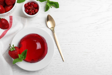 Delicious fresh red jelly with berries and mint on white wooden table, flat lay. Space for text - obrazy, fototapety, plakaty