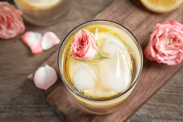 Delicious refreshing drink with lemon and rose on wooden table, top view