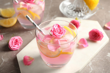 Delicious refreshing drink with lemon and roses on marble table