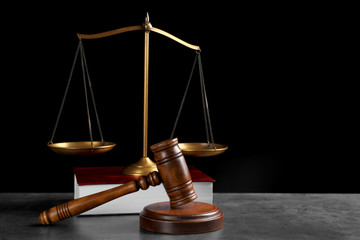 Judge's gavel, book and scales on grey table against black background, space for text. Criminal law...