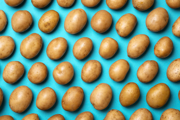 Raw fresh organic potatoes on blue background, flat lay