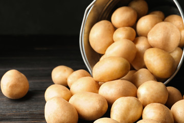 Raw fresh organic potatoes on black wooden table, closeup