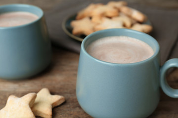 Composition with delicious hot cocoa drink and cookies on wooden table, closeup