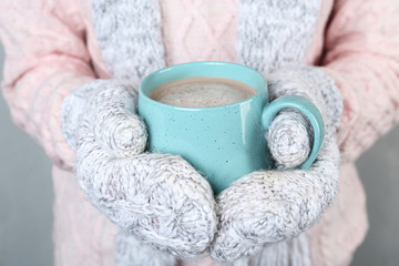 Woman with knitted mittens holding cup of delicious cocoa drink, closeup