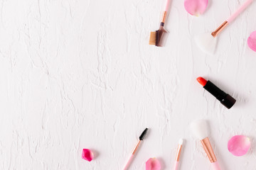 Top view of .beautiful makeup brushes with rose petals on white background.