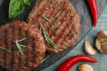 Grilled meat cutlets for burger on blue wooden table, top view