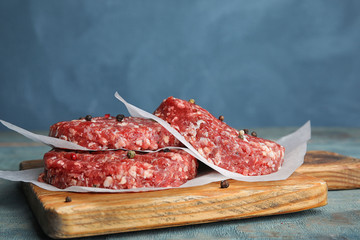 Raw meat cutlets for burger on blue wooden table. Space for text
