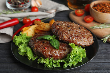 Grilled meat cutlets for burger on black wooden table