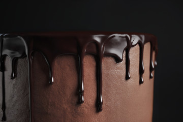 Freshly made delicious chocolate cake against black background, closeup