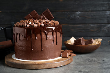 Freshly made delicious chocolate cake on grey table against black background. Space for text