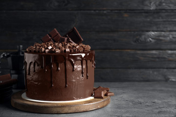 Freshly made delicious chocolate cake on grey table against black background. Space for text