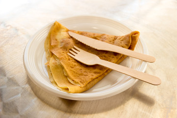 A crepe with wooden fork and knife under natural light