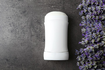 Female deodorant and lavender flowers on grey stone background, flat lay