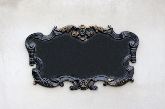 Vintage blank black metal wall plaque or sign with decorative swirly edges with gold coloring