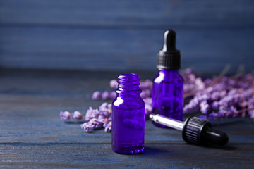 Bottles of lavender essential oil on blue wooden background