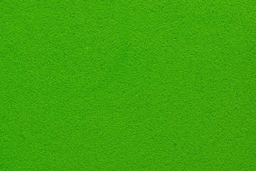 Plain green background of Kelly hue. Close up image of a rubber mat with small perforations.