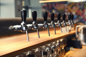 Row of shiny beer taps in pub