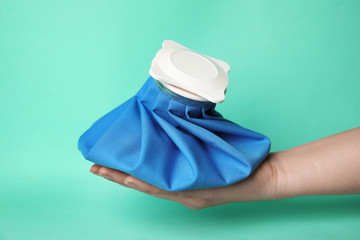 Woman holding ice pack against turquoise background, closeup