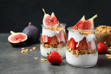 Jars of tasty homemade granola dessert on grey table. Healthy breakfast