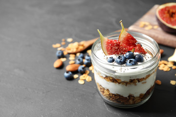 Tasty homemade granola dessert on dark grey table, space for text. Healthy breakfast