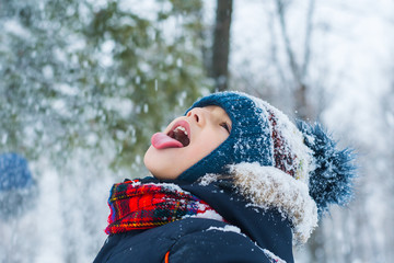  boy stuck out his tongue and catches snowflakes